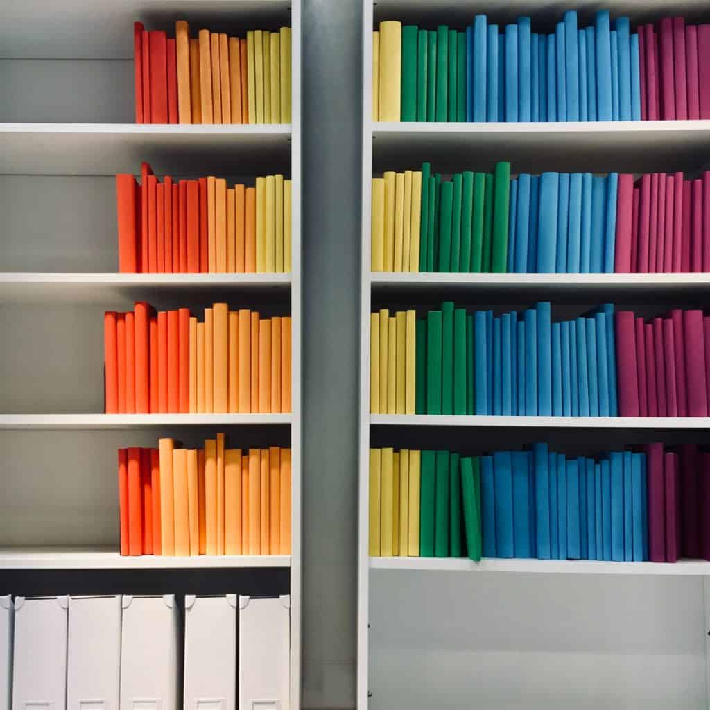 a photo of a bookcase with color coded books