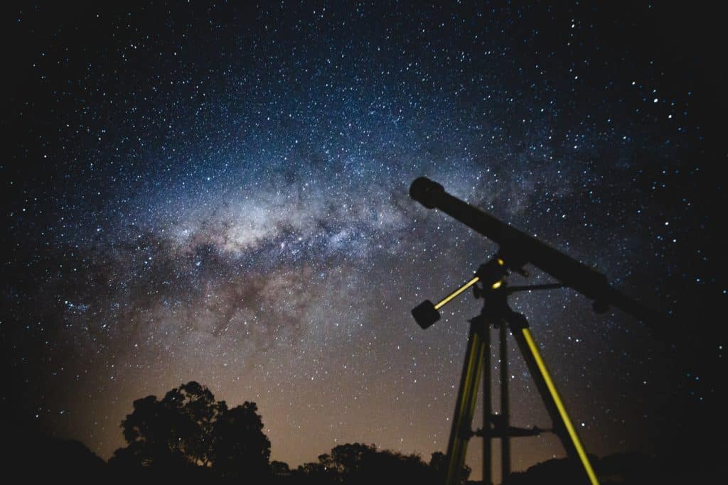 a photo of a telescope looking up to the midnight sky